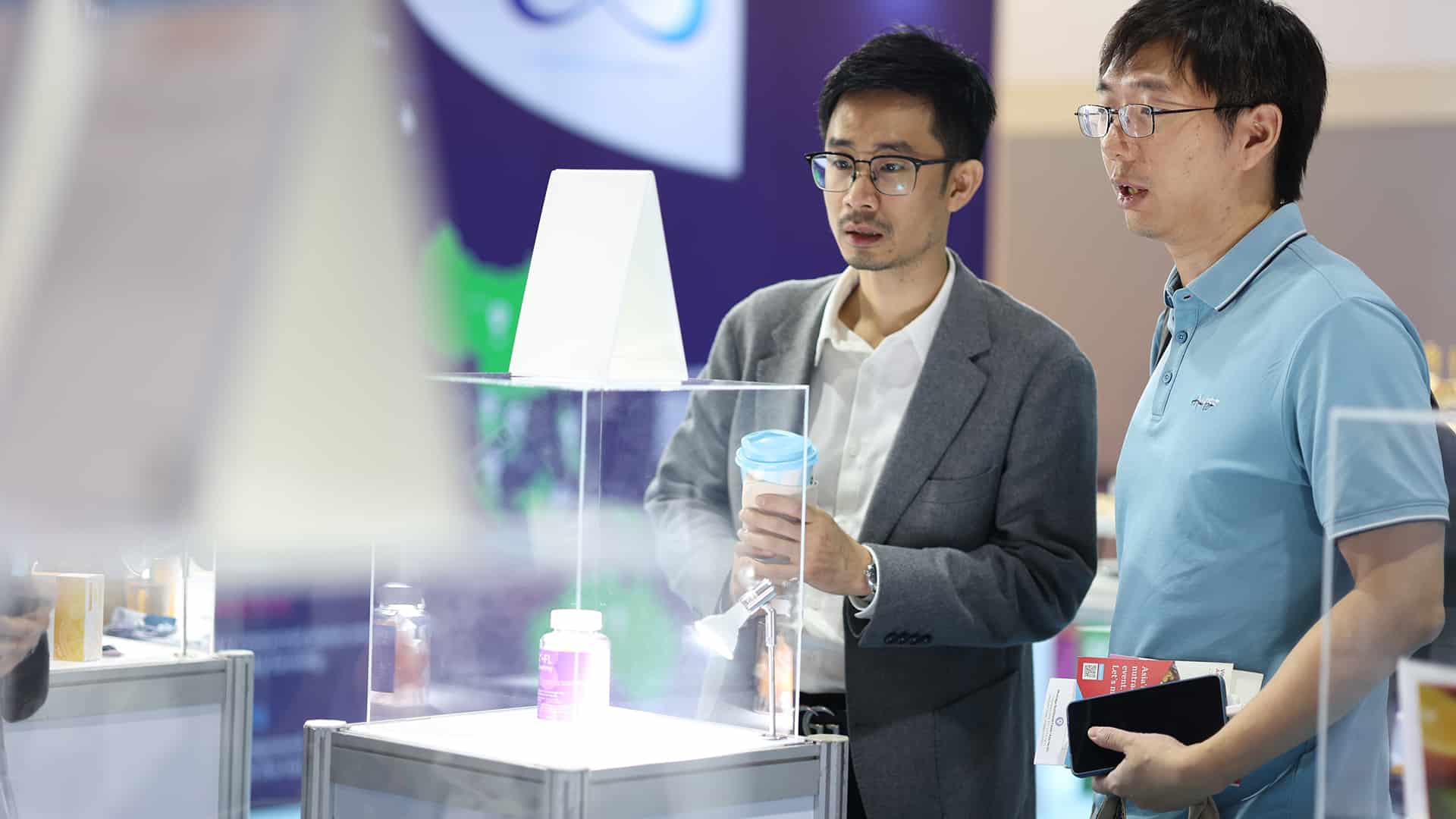 Two attendees at Vitafood Asia attentively looking at a booth